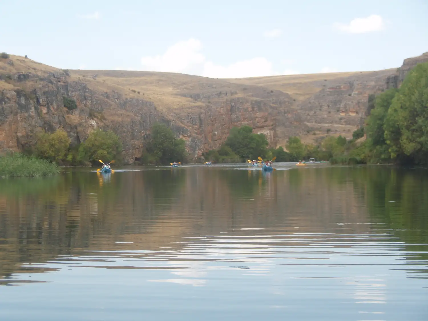 Piraguas en el embalse de Las Vencías, con cortados al fondo