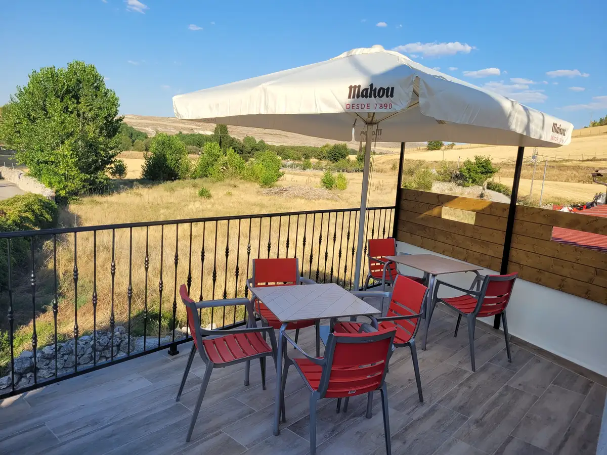Terraza en alto con mesas y sombrilla